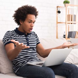 Shocked teen guy having problem in laptop