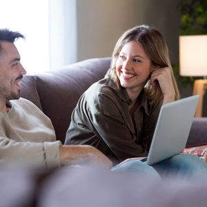 Beautiful young smiling couple using their laptop at home.