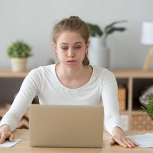 Confused woman looking at laptop screen, doing difficult computer work