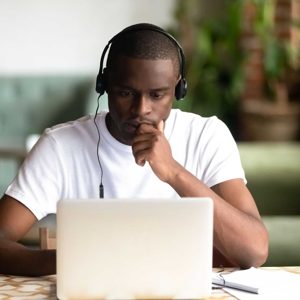 Focused African American man wear headphones, using laptop