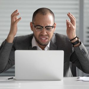 Angry african business man using laptop mad about computer problem