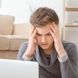 Depressed teenager using laptop on floor in room