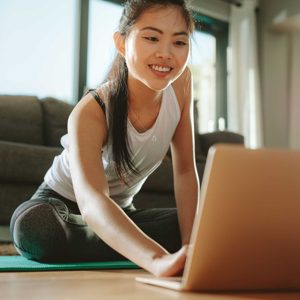 Woman using laptop while exercising at home
