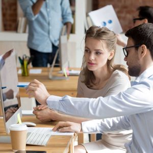 Executive manager teaching employee showing online project pointing on computer