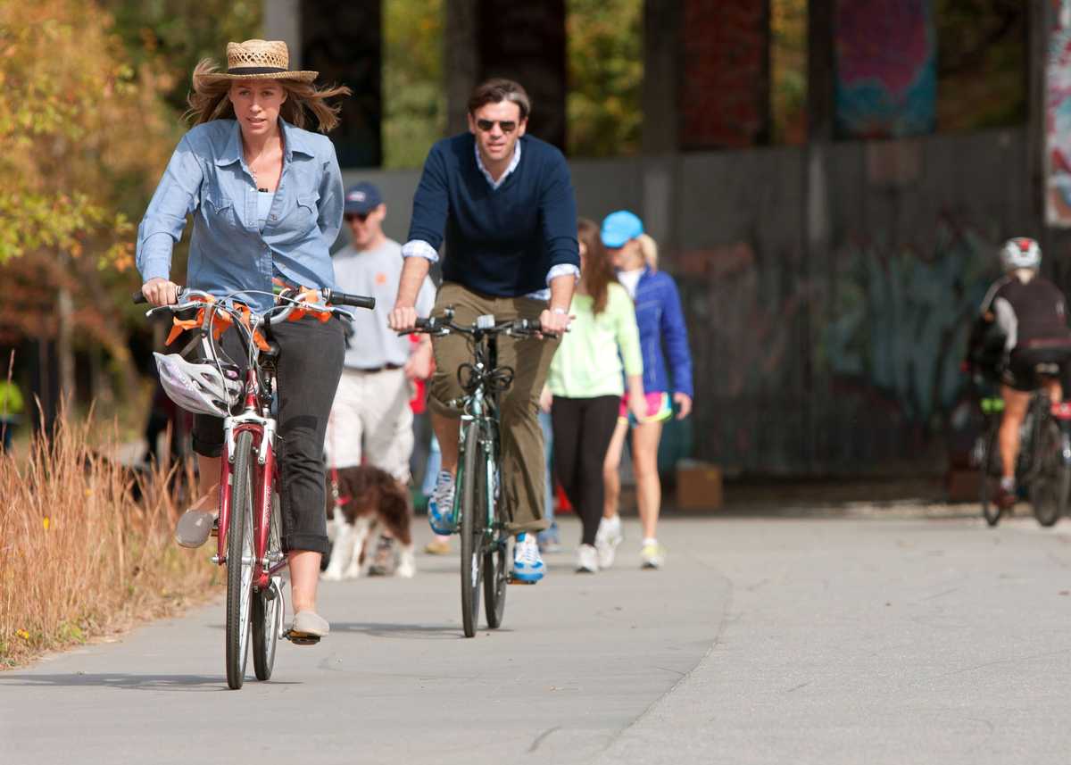 Atlanta, GA, USA - November 2, 2013:  A couple rides bikes as others exercise under a graffiti covered overpass that is part of the 22- mile Atlanta Beltline, an urban redevelopment project that will eventually connect 45 intown neighborhoods.