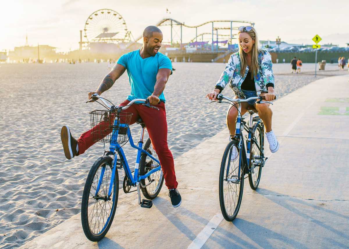 couple having fun riding bikes together at santa monica california