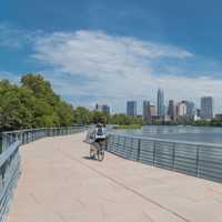 People biking running walking along Colorado River waterfront boardwalk near downtown Austin, Texas in summer day