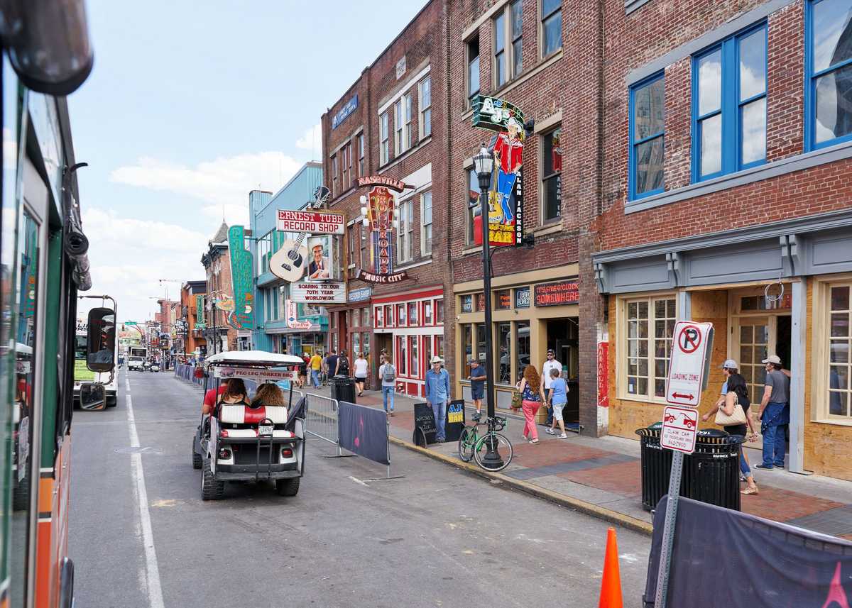 NASHVILLE, TN, USA - APRIL 14, 2017: Nashville's historic Broadway street, home to Ernest Tubb Record Shop, noisy and full of bars, entertainment, country music and visited by countless tourists on foot, in golf carts or busses.